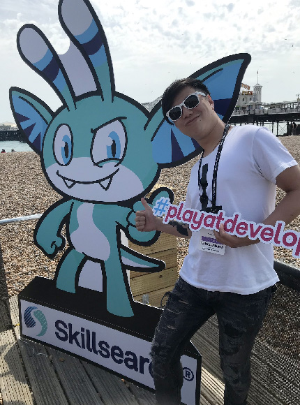 Young man in sunglasses posing in front of the Skillsearch mascot at the Play at Develop conference